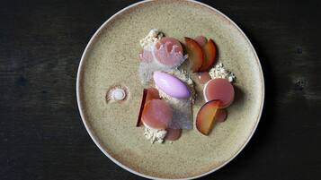 A round ceramic plate with various food items including slices of fruit and a decorative shell.