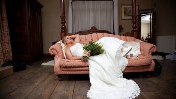 A bedroom with a four-poster bed, a wooden wardrobe, and a patterned sofa.