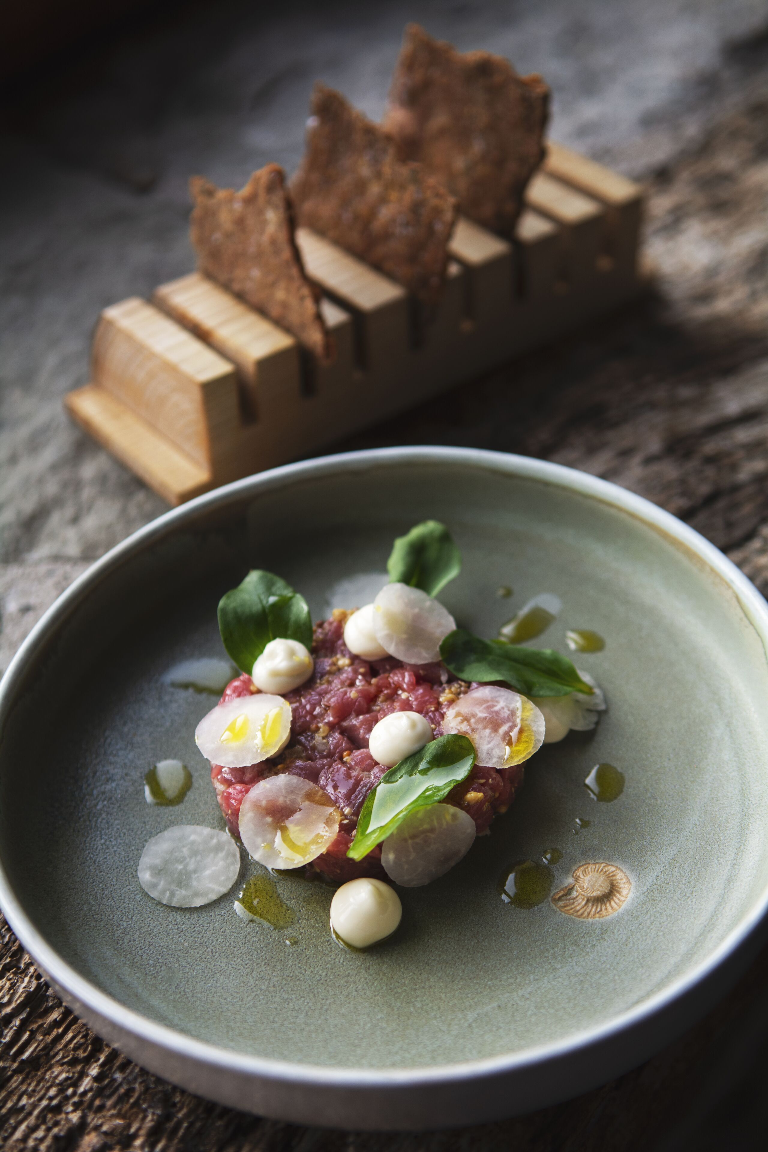 Un plato de comida con un recipiente verde, objetos blancos esféricos y hojas verdes.