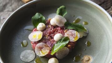 Un plato de comida con un recipiente verde, objetos blancos esféricos y hojas verdes.