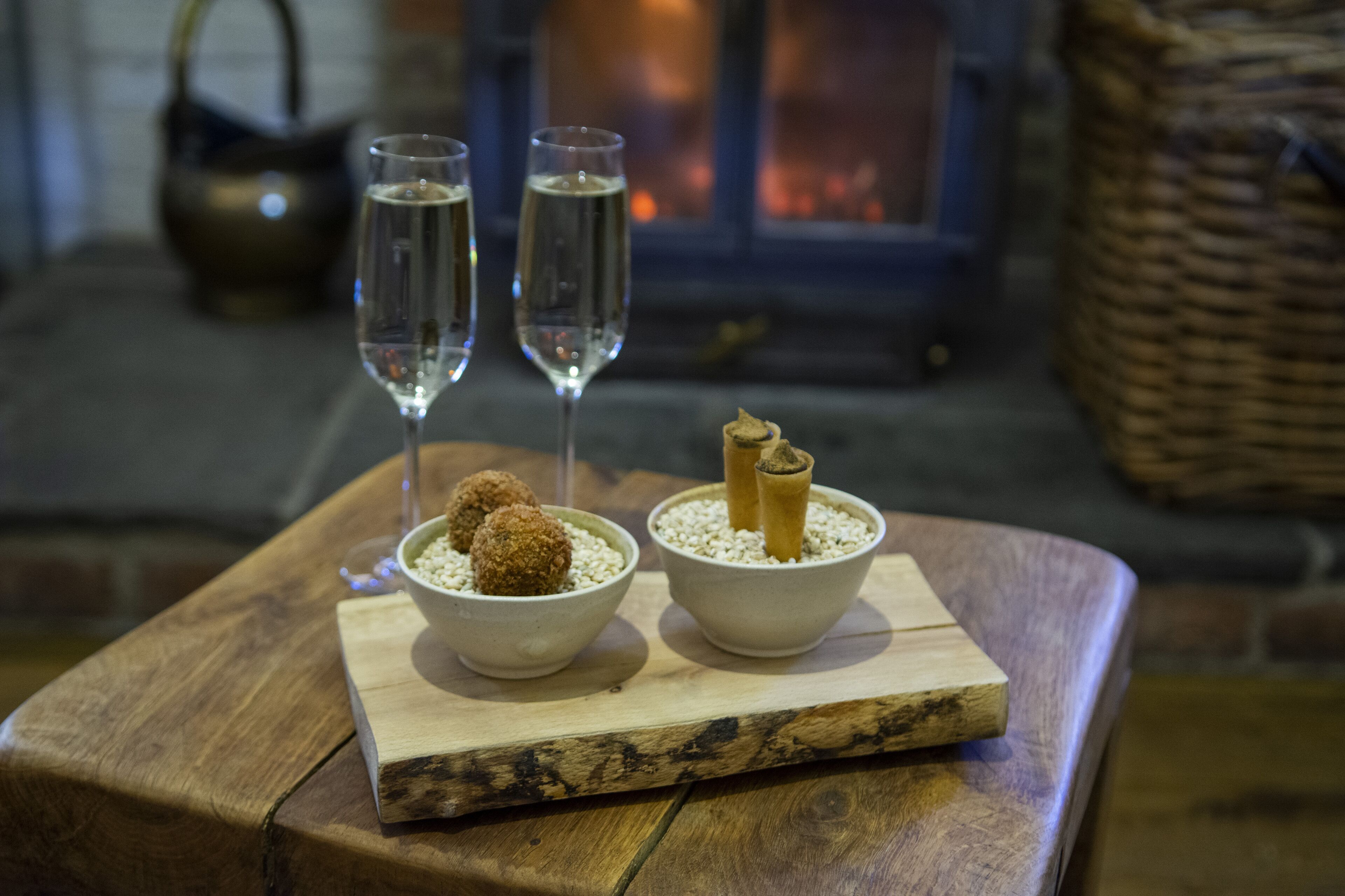 A wooden table with two bowls containing food items and two glasses of a clear liquid.