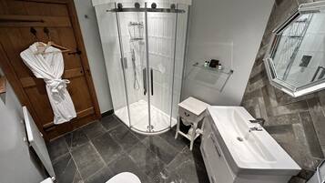 A modern bathroom with a glass-enclosed shower, a white sink, and a wooden door.