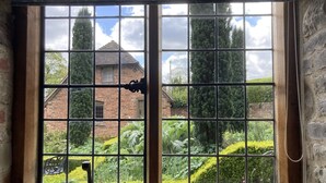 A large window with a view of a brick building and lush greenery. - Old Downton Lodge (Ludlow)