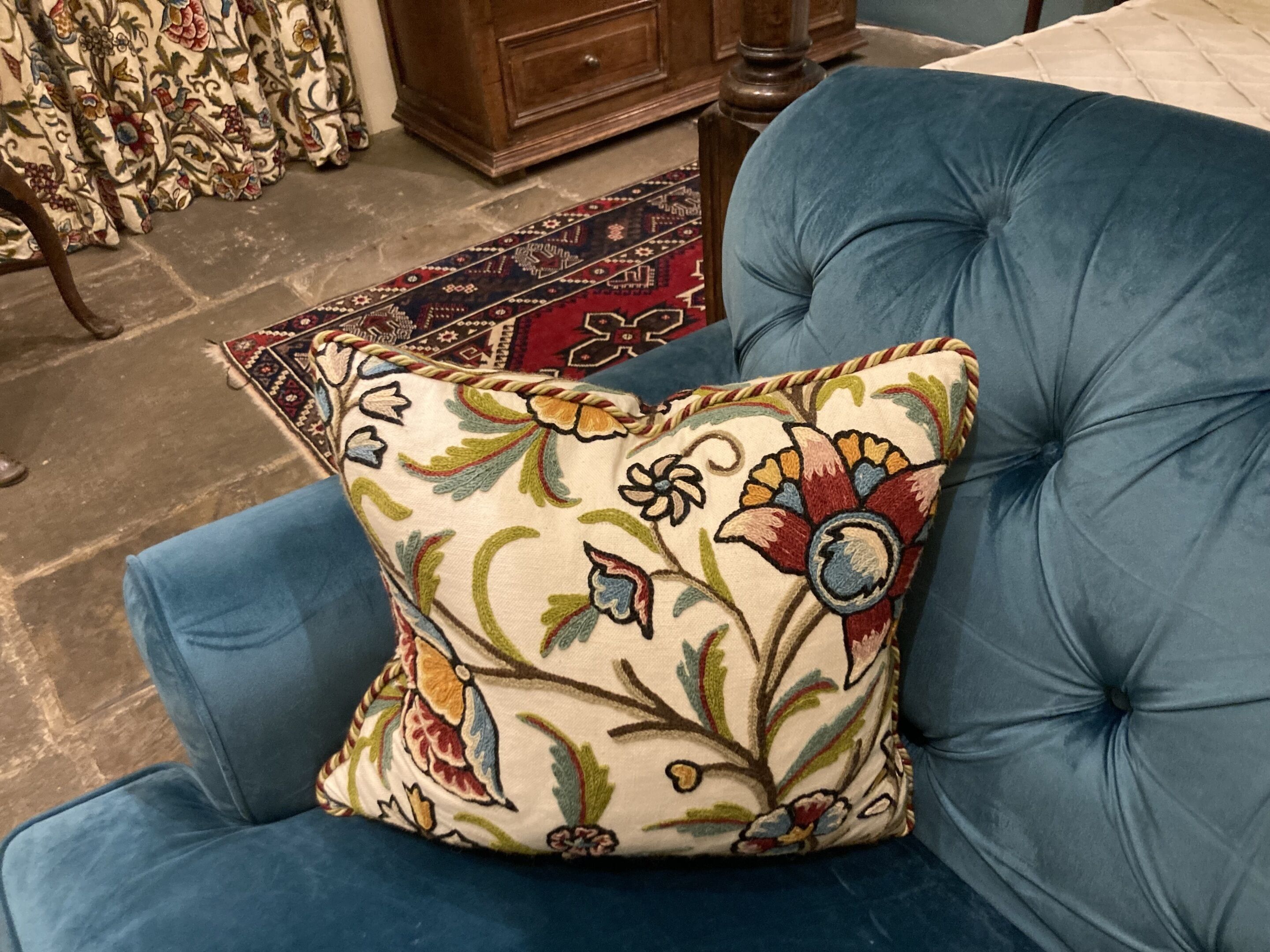 A blue upholstered chair with a floral-patterned pillow.