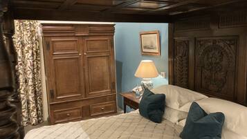 A bedroom with a large bed, a nightstand, a lamp, and a wardrobe.