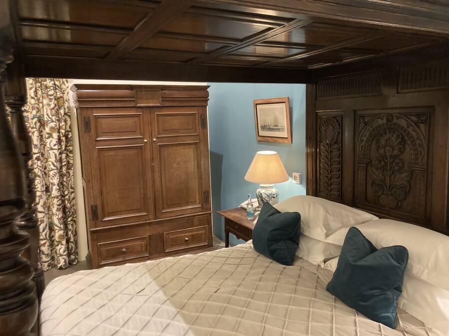 A bedroom with a large bed, a nightstand, a lamp, and a wardrobe.