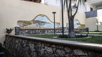 A stone wall with a mosaic mural depicting a coastal scene.