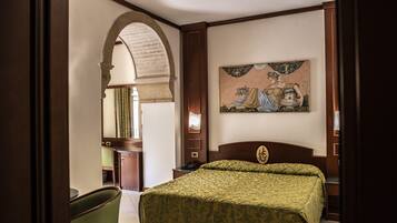 A hotel room with a large bed, a desk, a chair, and a painting on the wall.