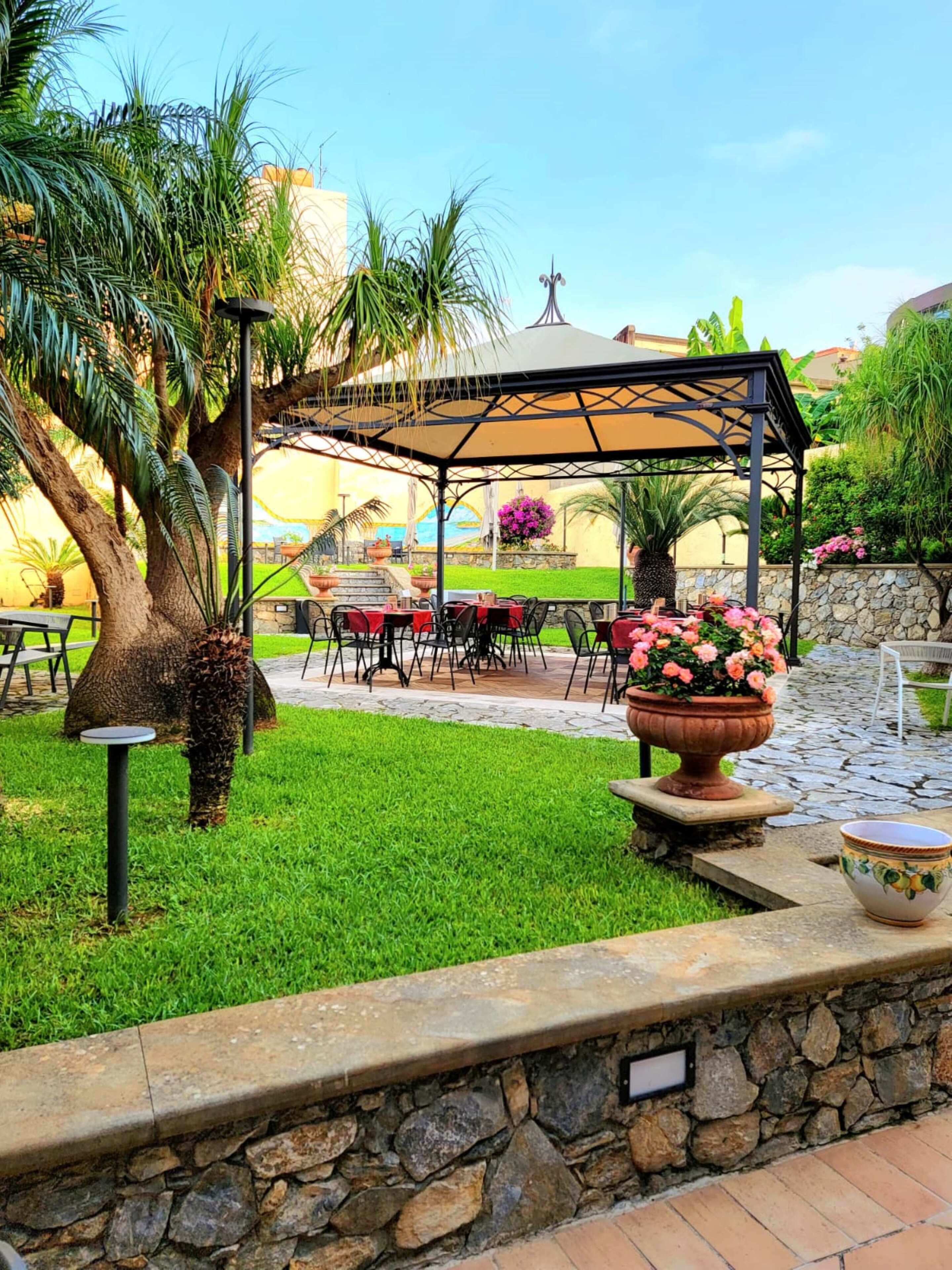 A patio area with outdoor seating, a pergola, and a stone wall.