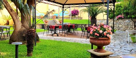 A patio area with outdoor seating, a pergola, and a stone wall.