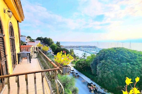 A balcony with a view of a coastal road, a bridge, and a body of water.