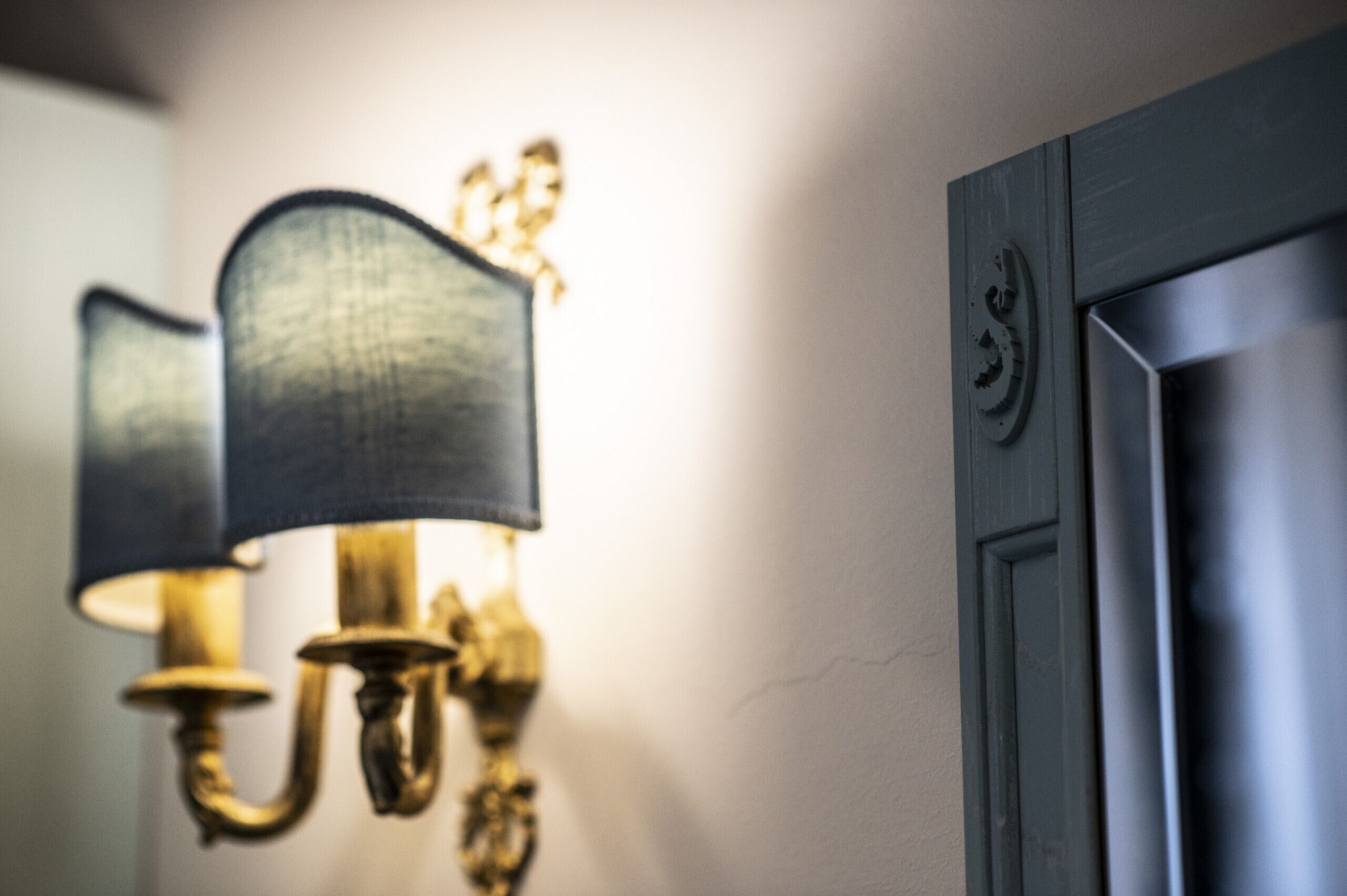 A close-up of a wall-mounted lamp with a textured shade and a brass base.