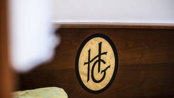 Une tête de lit en bois ornée d’un emblème circulaire représentant un logo stylisé « TG ».