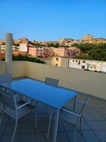 Terraza con mesa y sillas, con vistas a una zona residencial con edificios y vegetación.