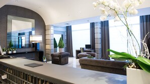 En modern hotellobby med en receptionsdisk, en sittgrupp och stora fönster.