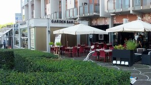 En hotellentrén med utomhusservering, en trädgårdsbar och en överbyggd entré.
