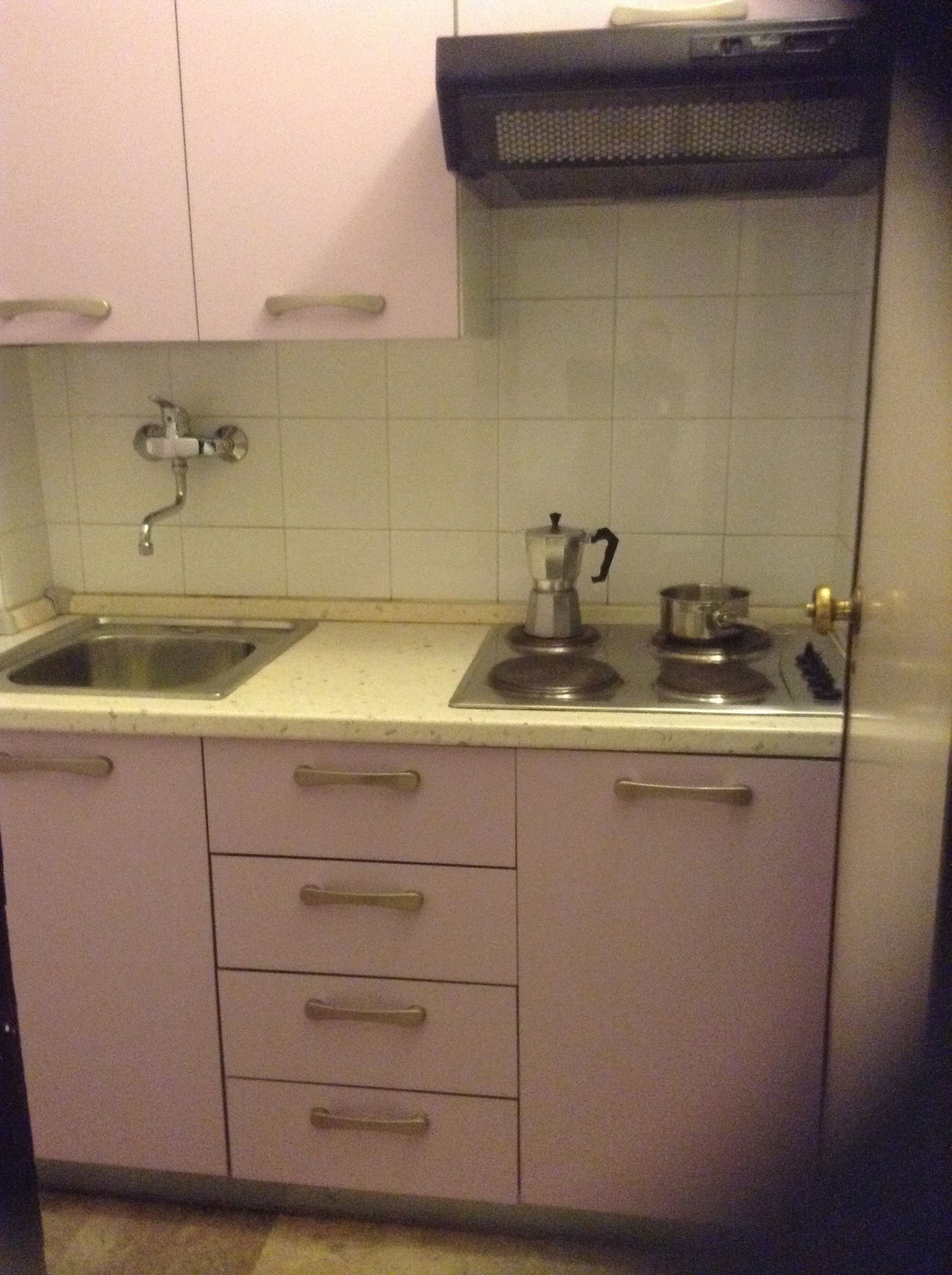 Una cocina con pileta, estufa y alacenas.