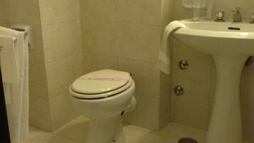 Une petite salle de bain avec des toilettes, un lavabo et un porte-serviettes.