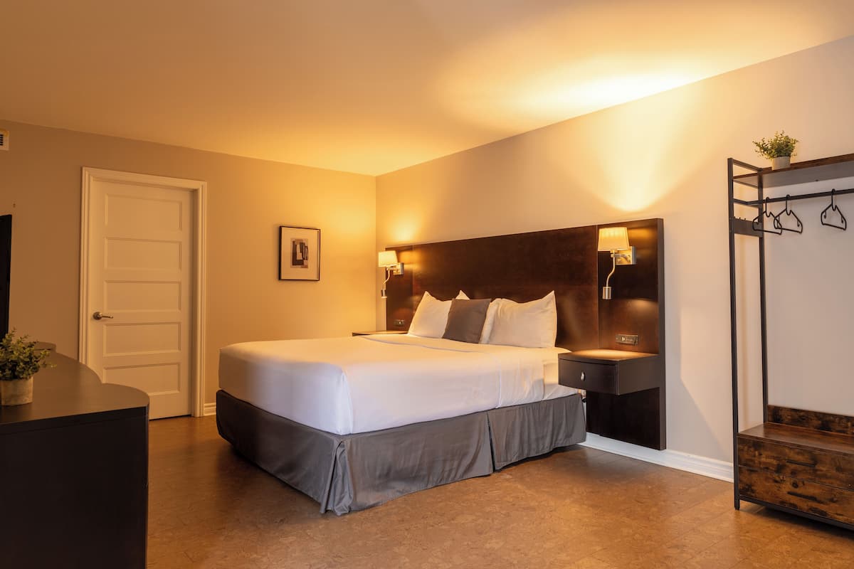 A neatly arranged hotel room with a bed, bedside tables, a wardrobe, and a door.