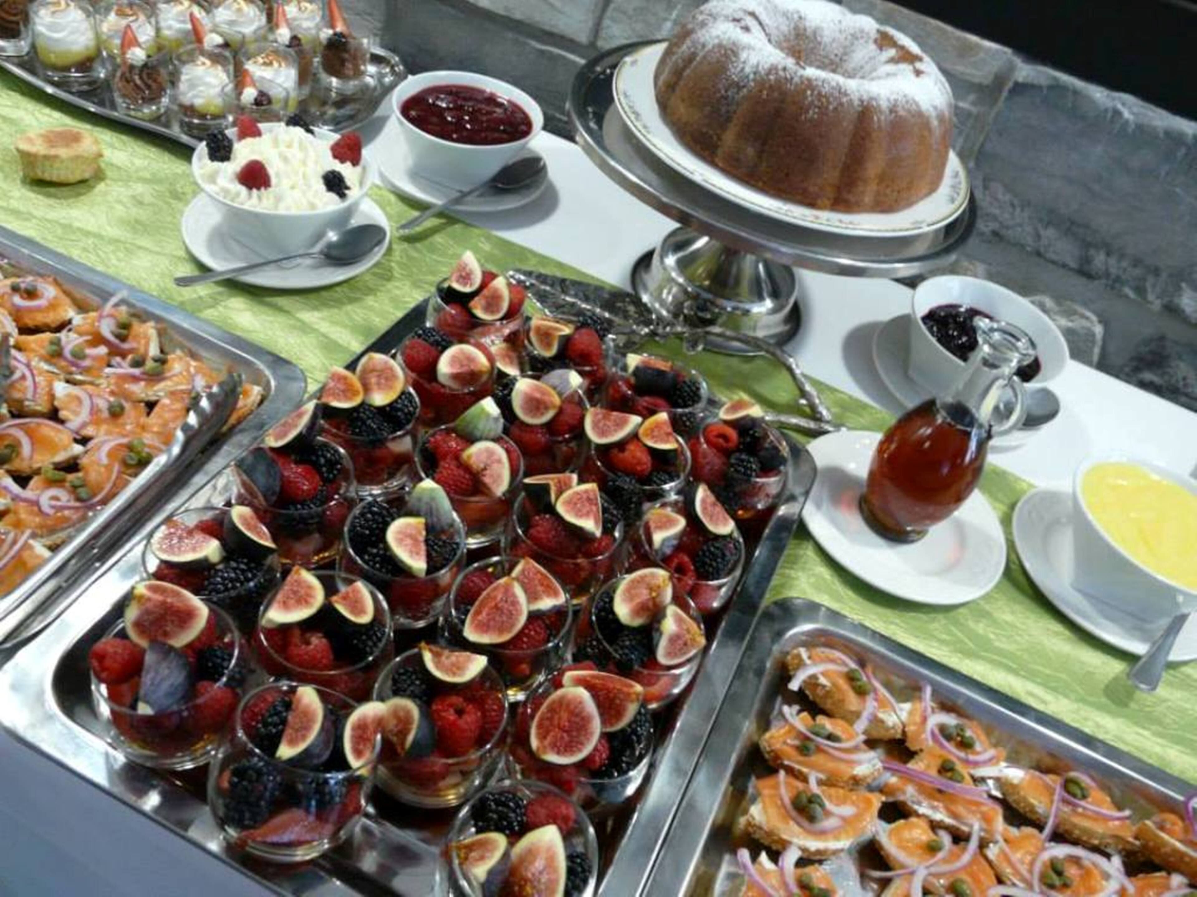 Un bufé con diferentes opciones de comida, incluyendo frutas, pasteles y un pastel bundt.