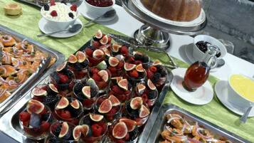 Un bufé con diferentes opciones de comida, incluyendo frutas, pasteles y un pastel bundt.