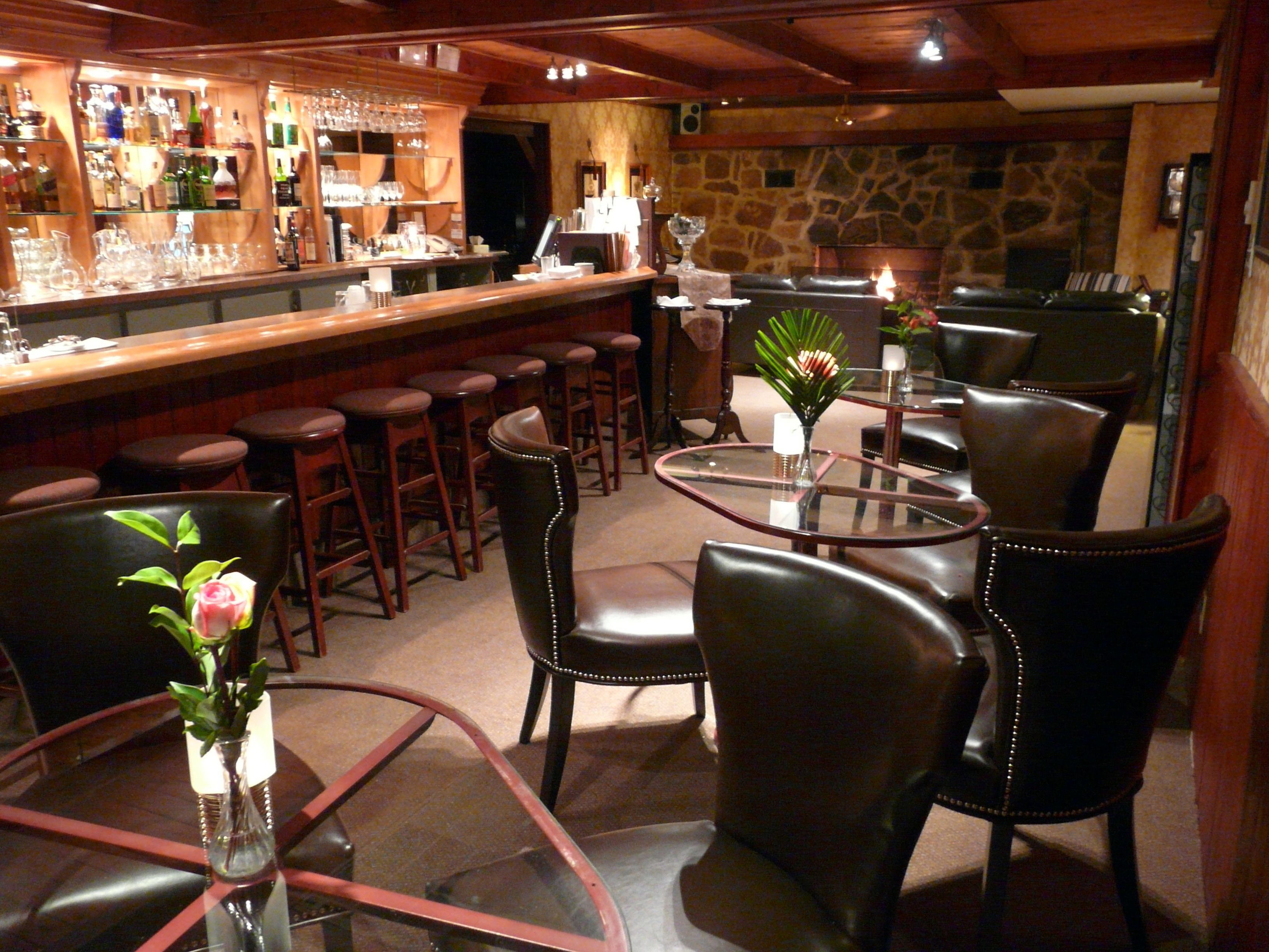 A bar area with stools, a fireplace, and a table with chairs.