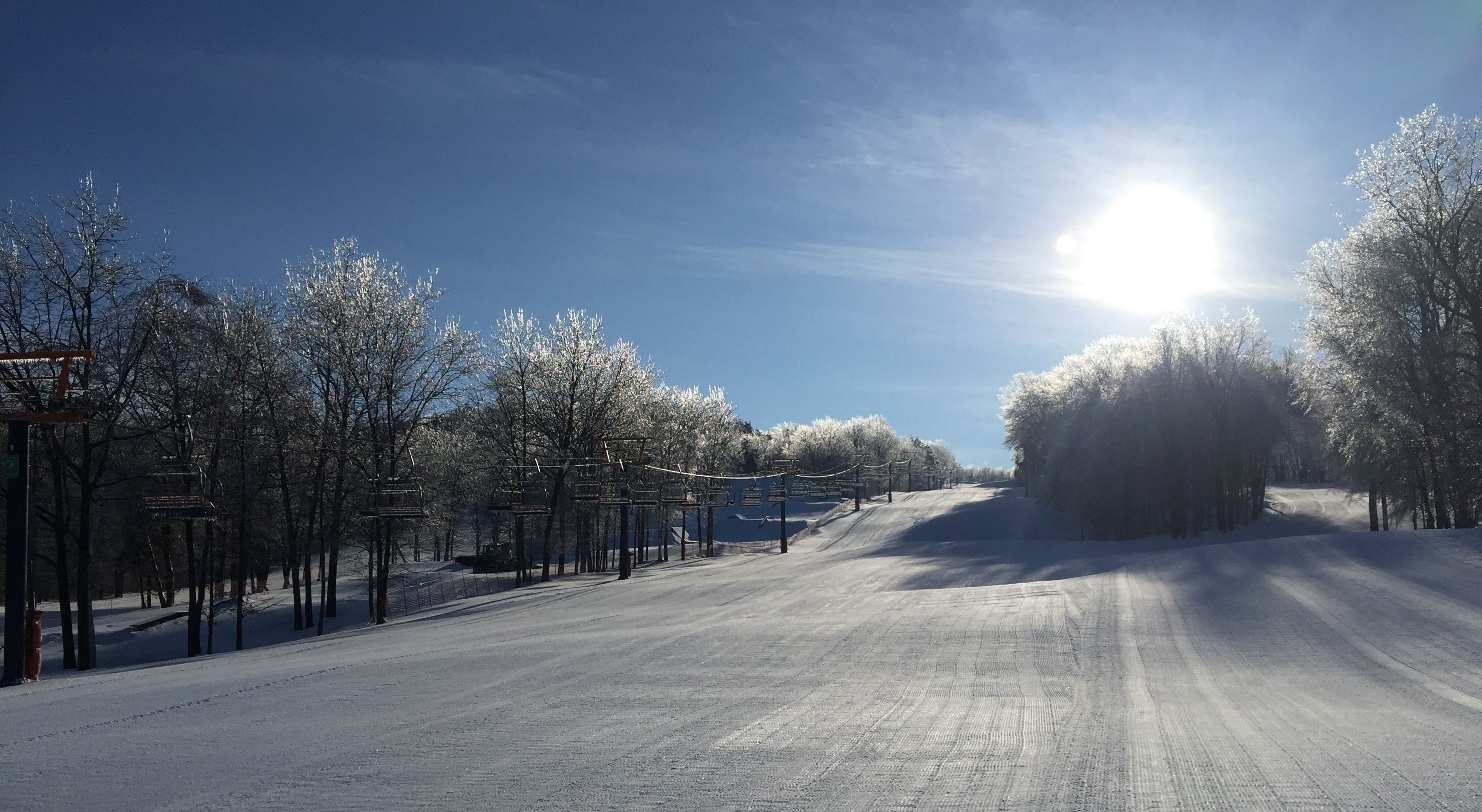 A snowy road with a ski lift and trees.