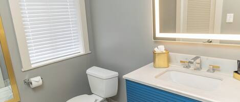 Une salle de bain avec des toilettes, un lavabo et un miroir.