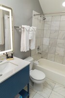 Un baño moderno con lavamanos blanco, tocador azul, inodoro y bañera.