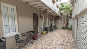 Un patio con piso de ladrillo, mobiliario exterior y plantas en macetas.