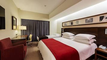 Una habitación de hotel con una cama grande, un escritorio, una silla, una lámpara y un teléfono.