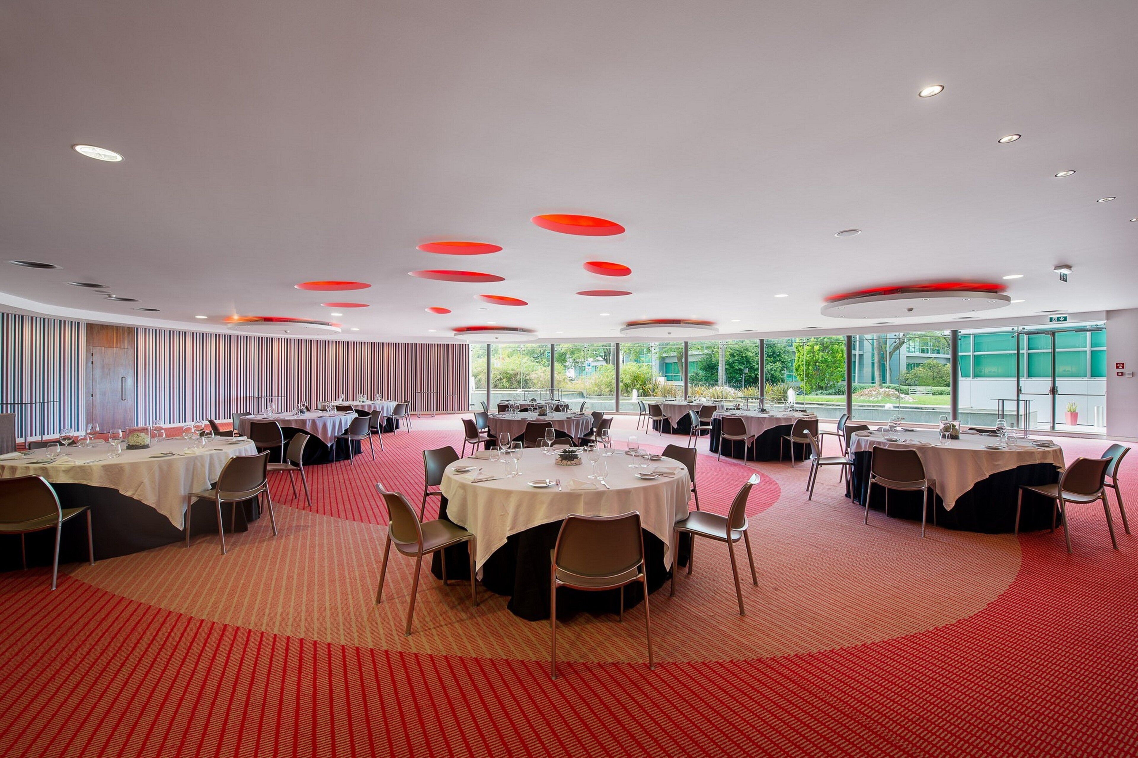 A conference room with round tables, chairs, and a red carpeted floor.