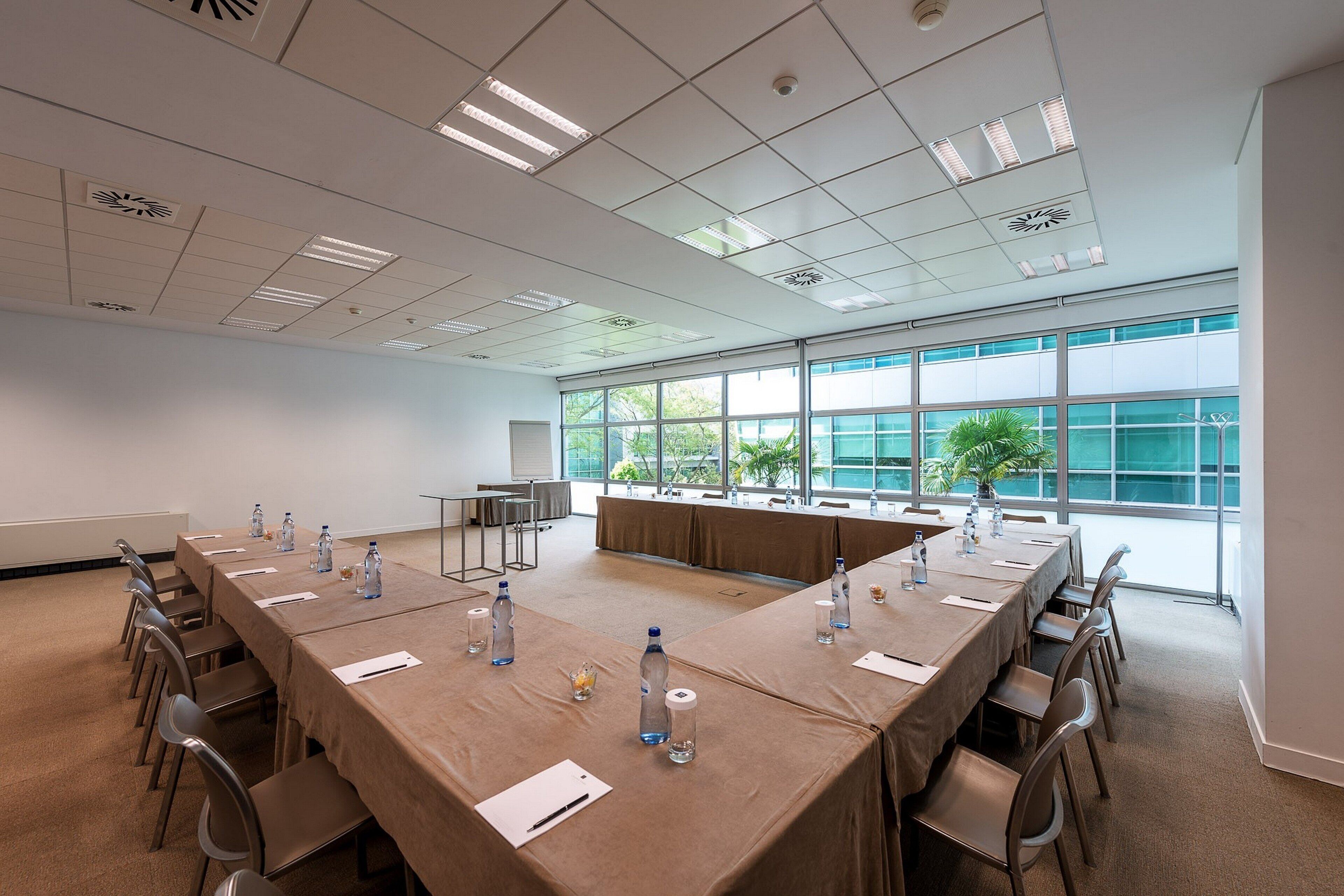 Un salón de conferencias con una larga mesa, sillas, botellas de agua y una pizarra.