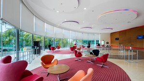 En rummelig lobby med moderne møbler, store vinduer og et buet loftdesign.
