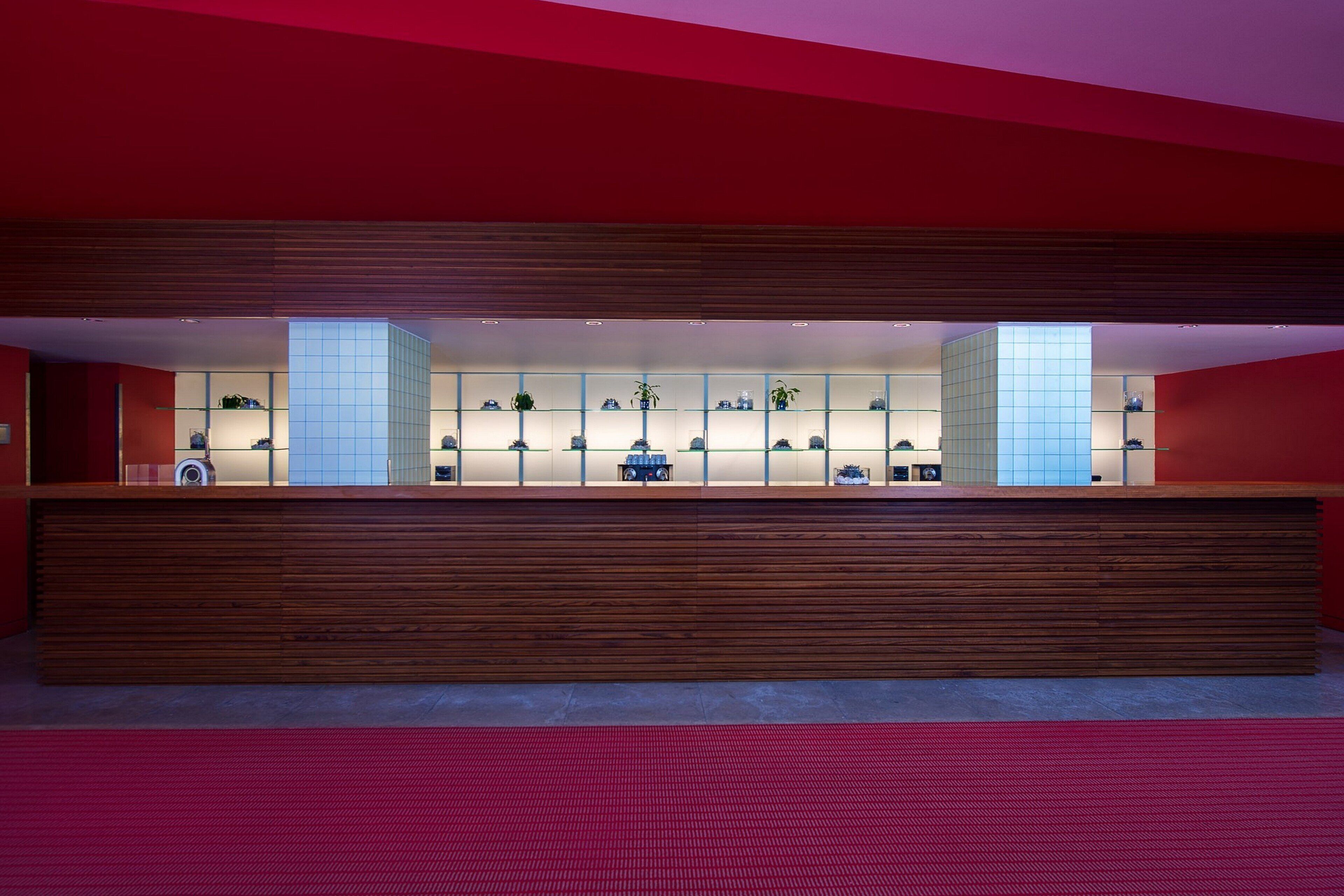 A reception area with a wooden counter, glass display cases, and a red carpet.