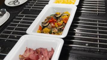 Una mesa de buffet con tres opciones: verduras a la parrilla, huevos revueltos y tocino.