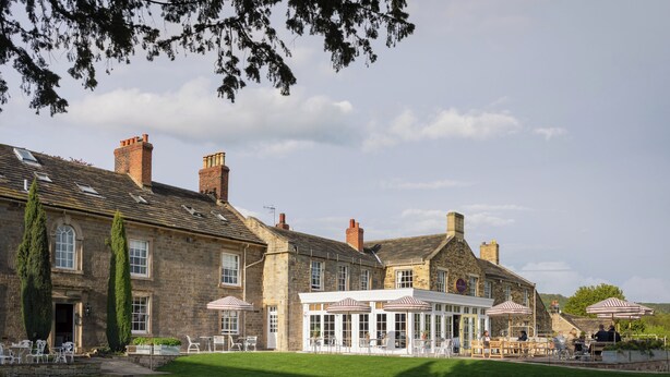 A traditional stone building with a large patio area, outdoor seating, and a well-maintained lawn. - Cavendish Hotel (Bakewell)