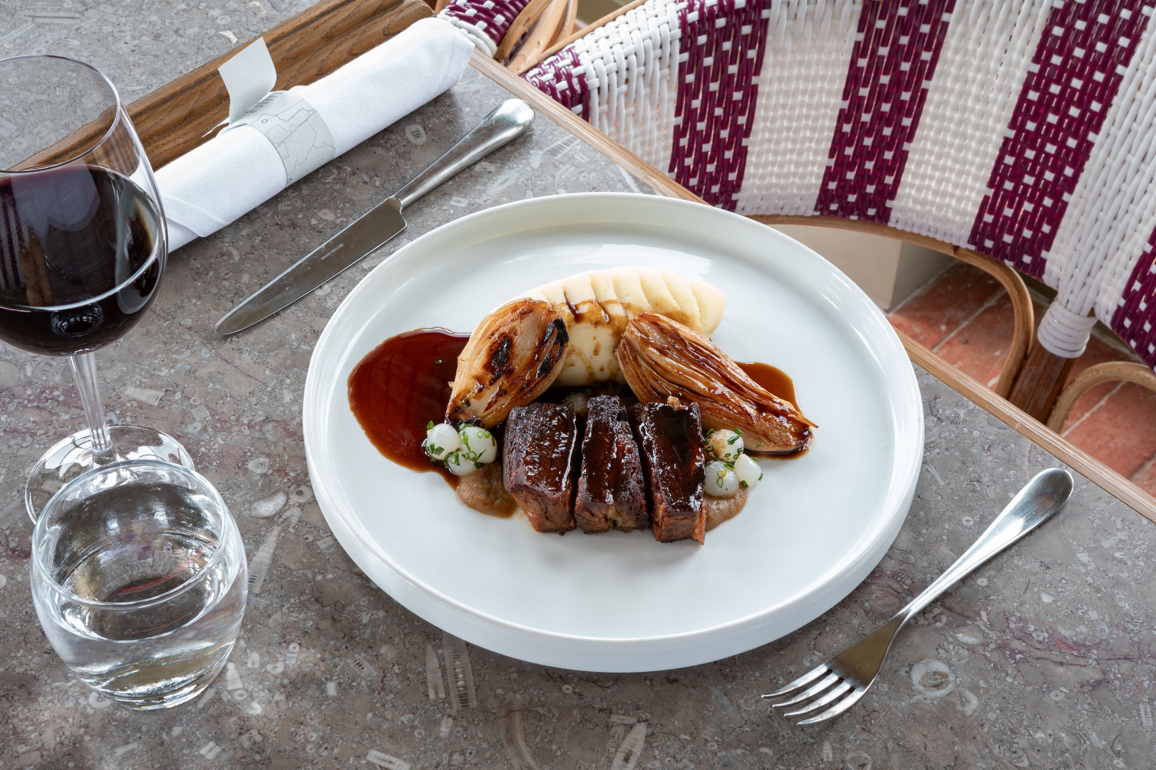 A plate with steak, mashed potatoes, and sauce on a table.