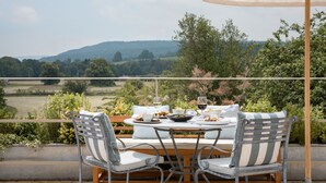 A dining table set outdoors with a view of a countryside landscape. - Cavendish Hotel (Bakewell)