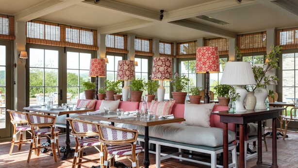 A spacious patio area with a dining table, chairs, and a sofa. There are potted plants and a large window with bamboo shades. - Cavendish Hotel (Bakewell)