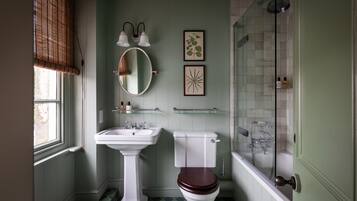 A bathroom with a pedestal sink, a toilet, a mirror, and a shower.