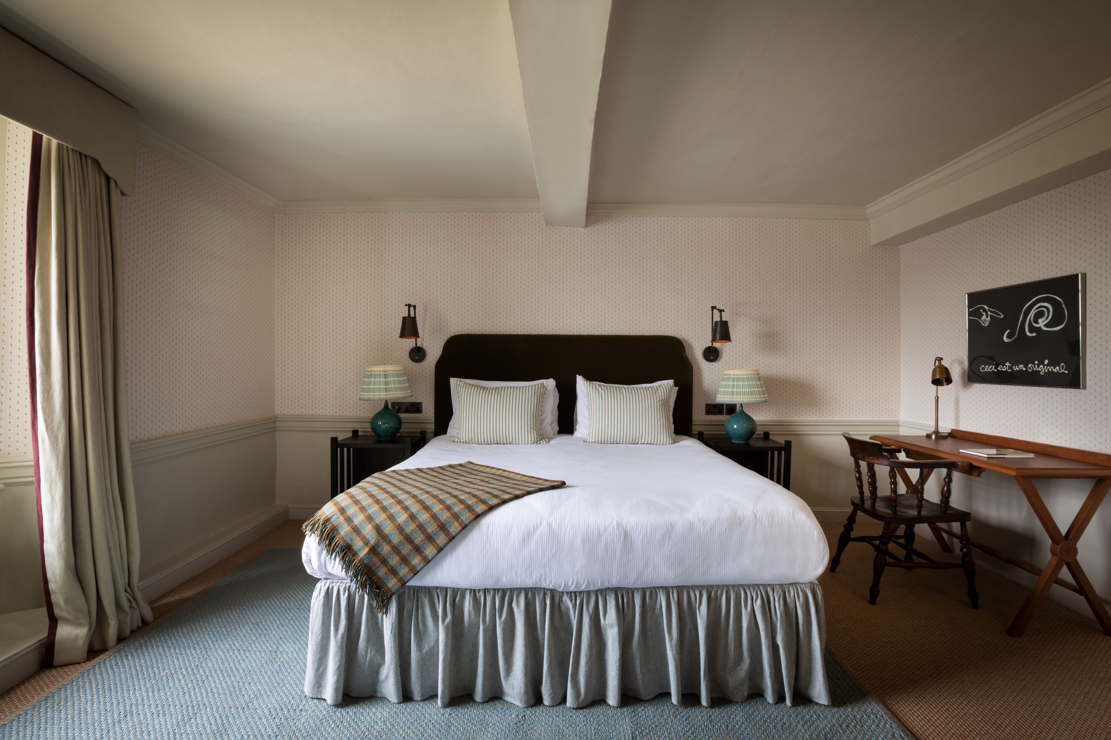 A neatly arranged bedroom with a large bed, two bedside tables with lamps, a desk, and a chair.