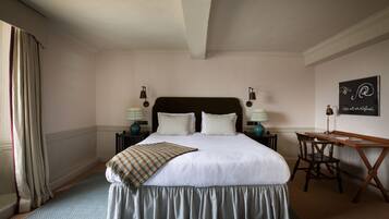 A neatly arranged bedroom with a large bed, two bedside tables with lamps, a desk, and a chair.
