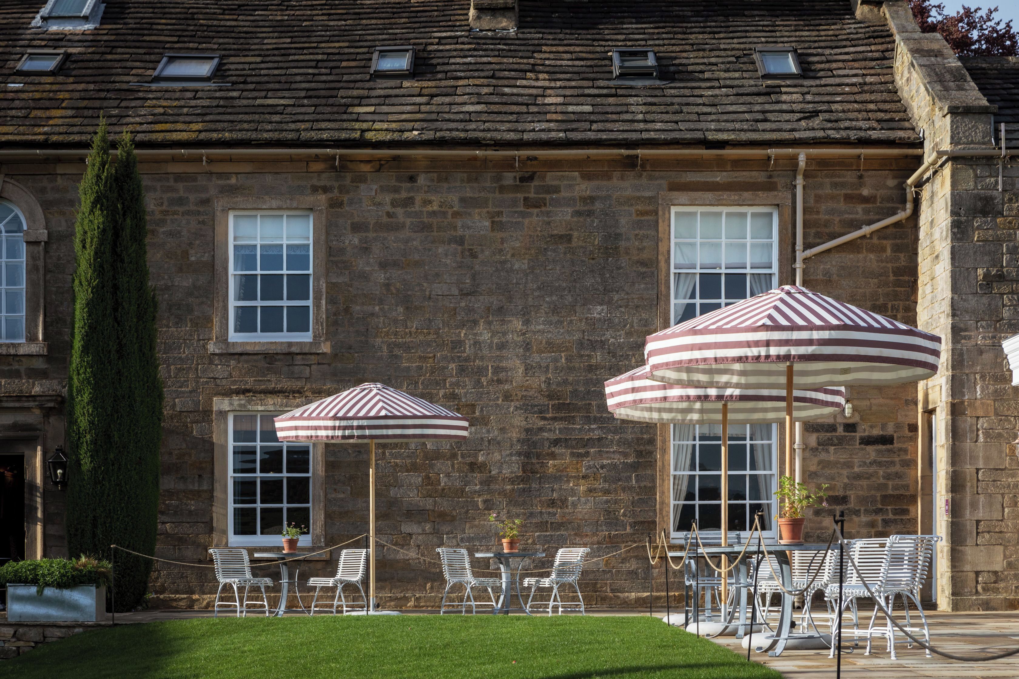 A stone building with a traditional brick facade, large windows, and a well-maintained lawn with outdoor seating.