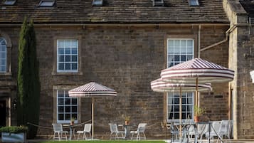 A stone building with a traditional brick facade, large windows, and a well-maintained lawn with outdoor seating.