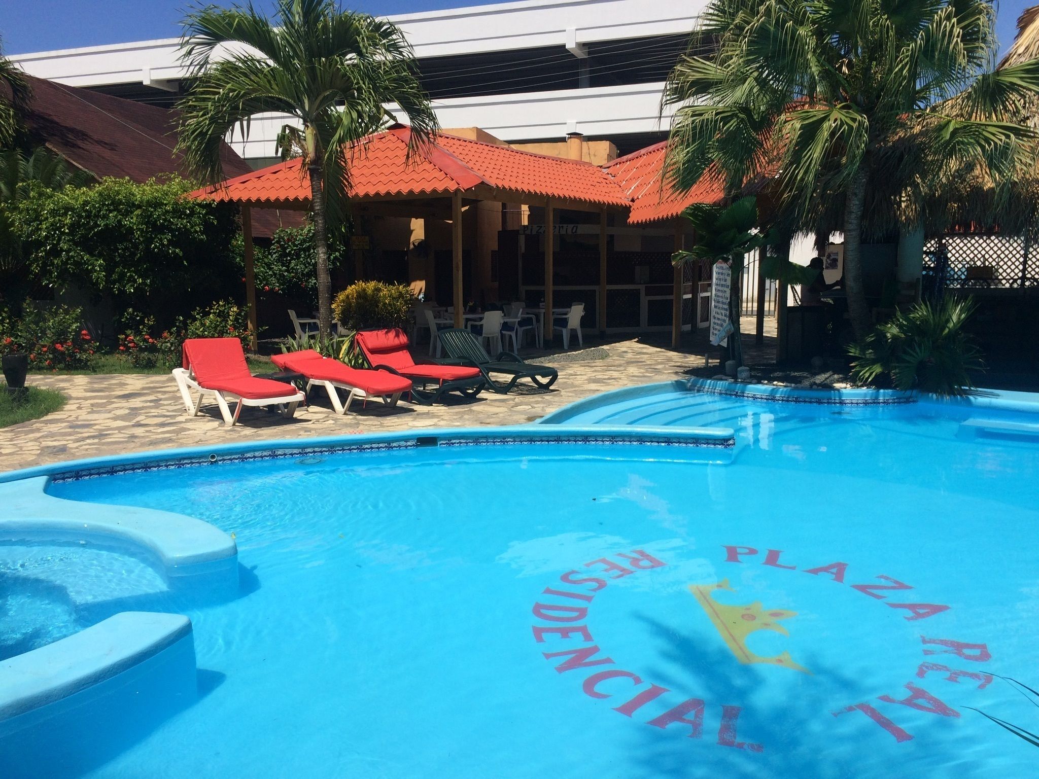 Una piscina con sillones de descanso y palmeras.