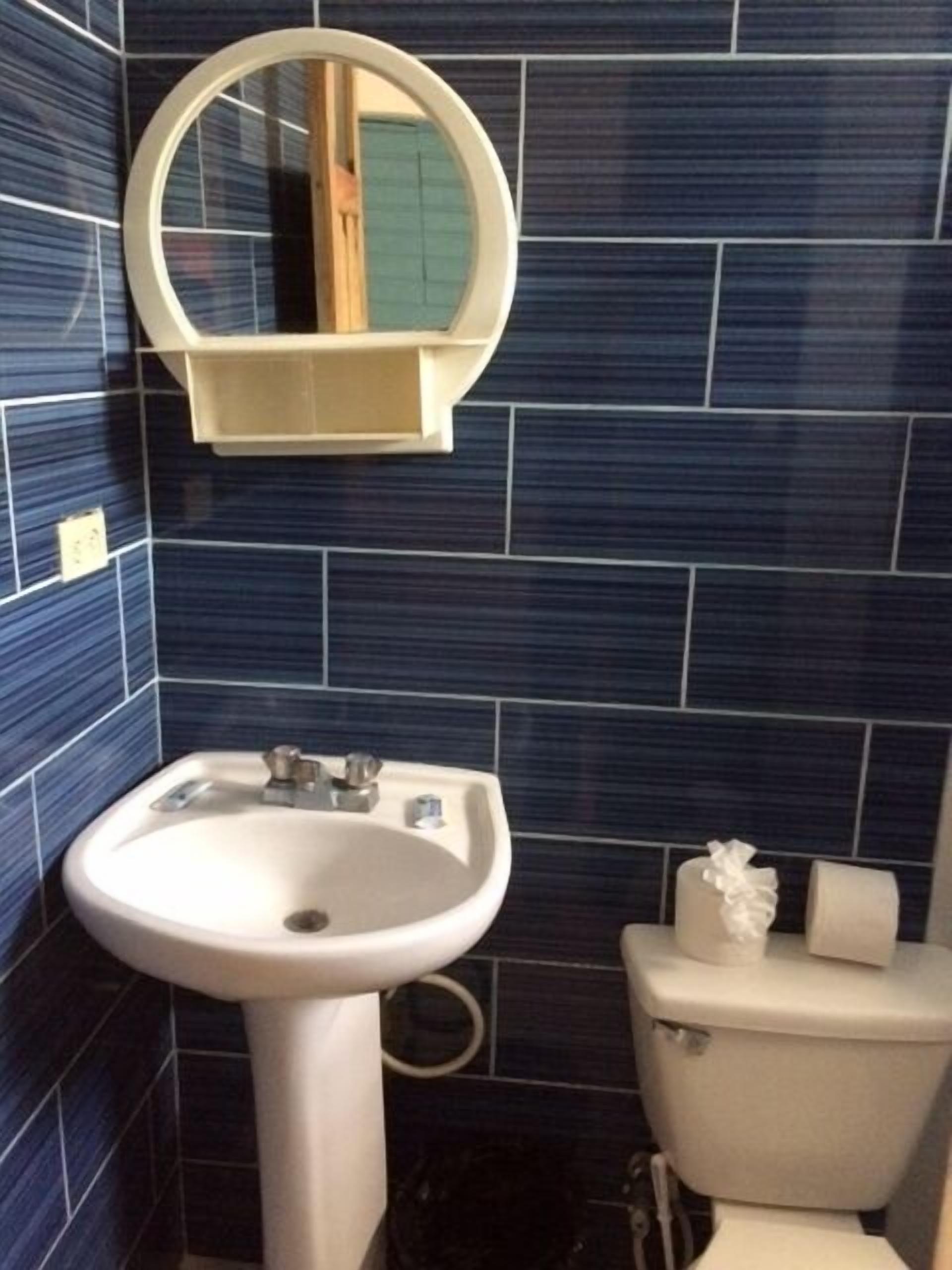 Ein Badezimmer mit einem weißen Waschbecken, einer Toilette und einem Spiegel über dem Waschbecken.