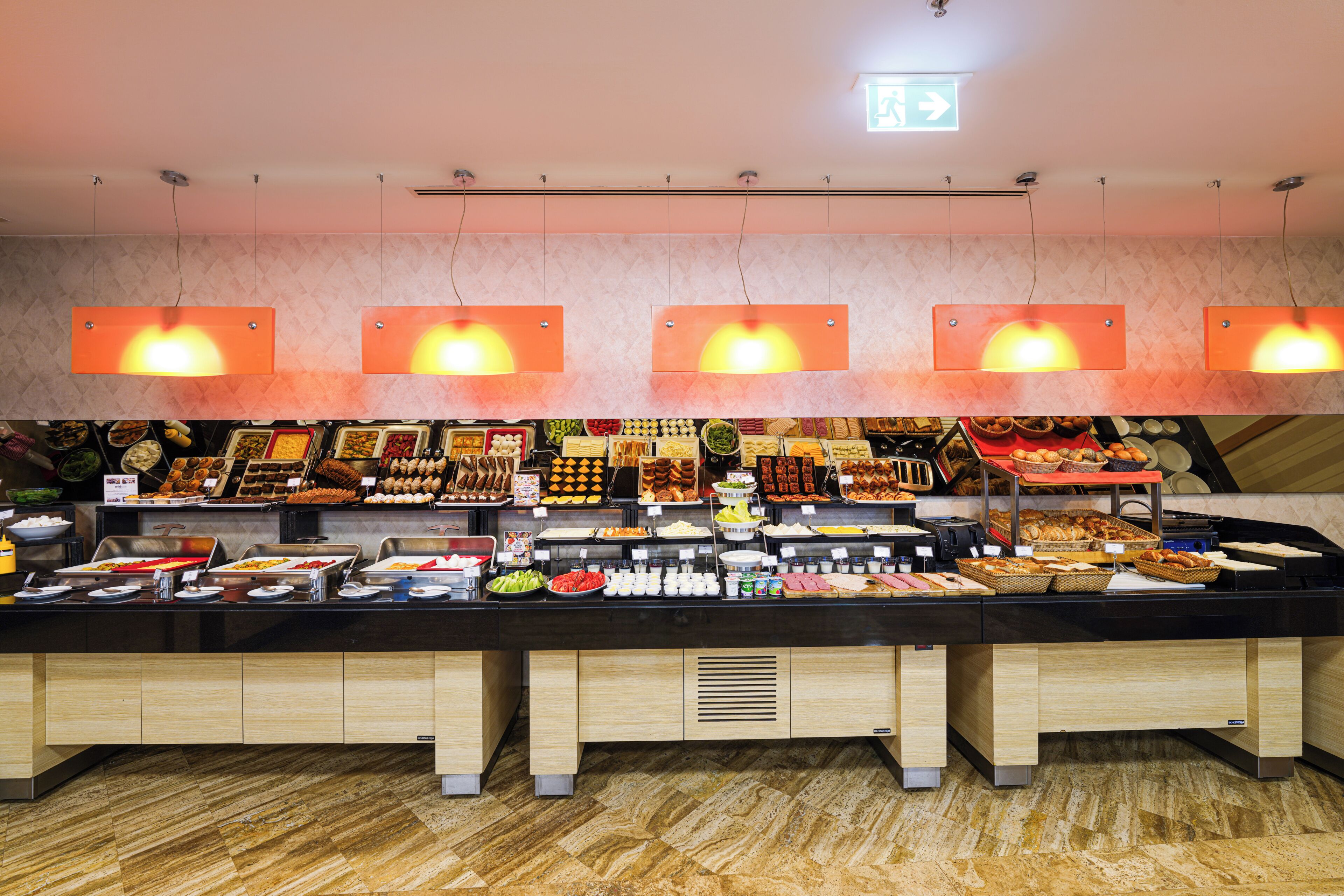 A buffet with various food items and a ceiling with hanging lights.