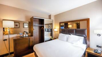 Ein Hotelzimmer mit einem großen Bett, einem Kleiderschrank, einem Schreibtisch und einem Spiegel.