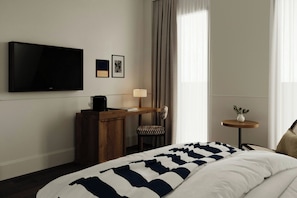 A hotel room with a bed, a desk with a lamp, a television, and a small table with a plant. - Jadran, Rijeka, a Tribute Portfolio Hotel (Rijeka)